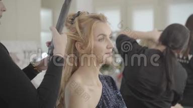 年轻漂亮的白人女子坐在美容院做发型的专业美发师的画像。造型师